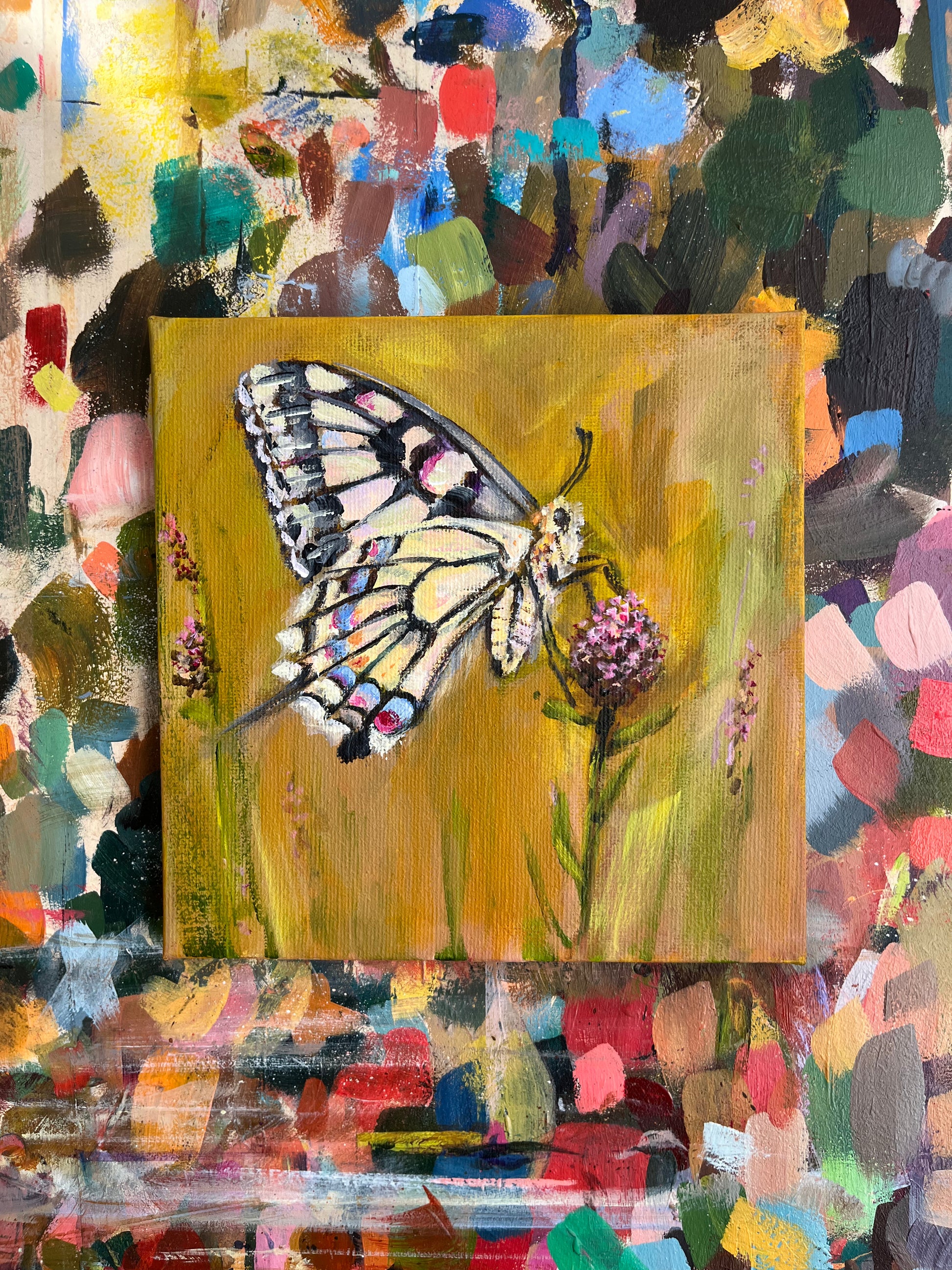 Painting of a butterfly on a flower with a colorful abstract background