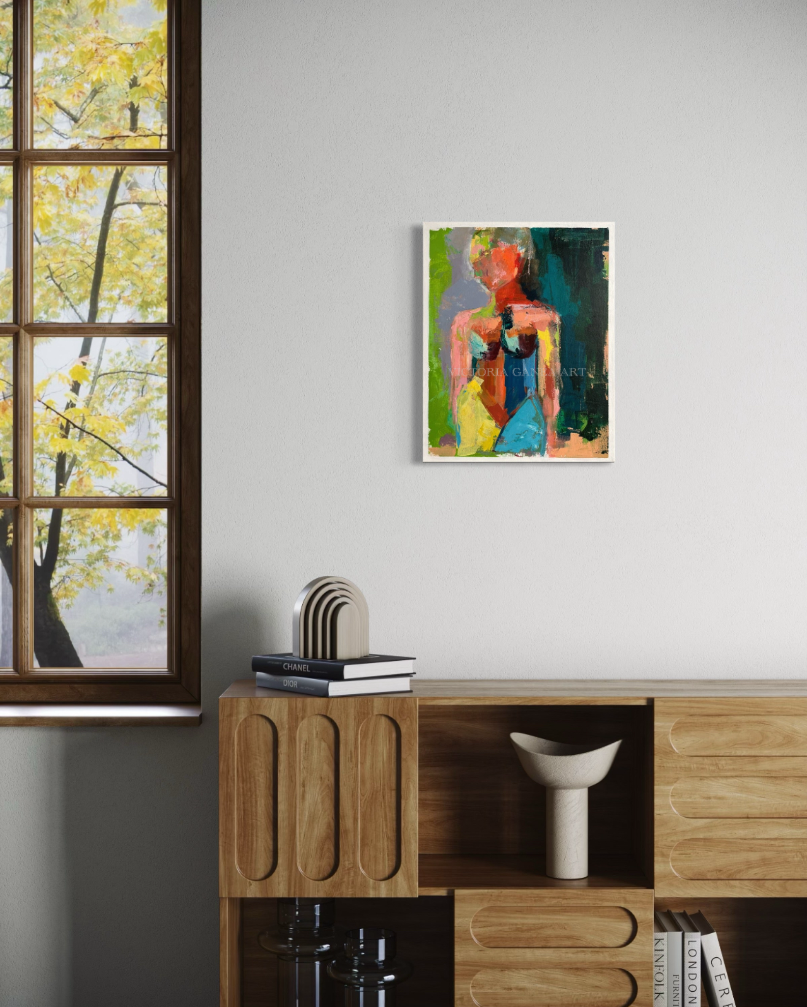 Colorful abstract painting of a woman on a wall above a wooden cabinet.